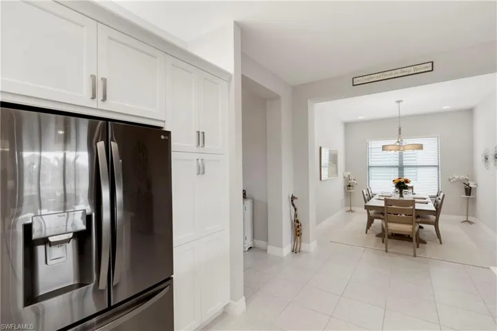 Kitchen featuring pendant lighting, light tile patterned floors, stainless steel fridge with ice dispenser, and white cabinets