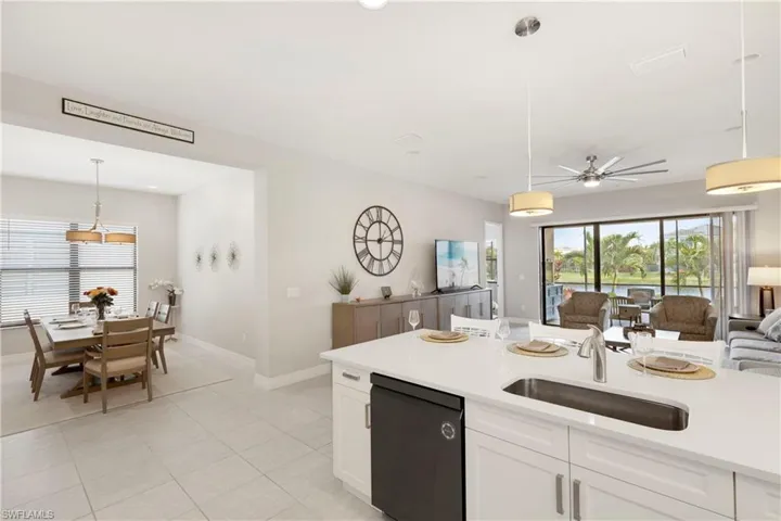 Kitchen featuring sink, white cabinetry, light tile patterned floors, dishwasher, and pendant lighting