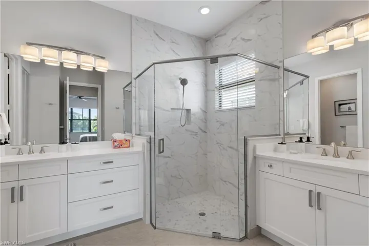 Bathroom featuring vanity, a shower with shower door, and ceiling fan