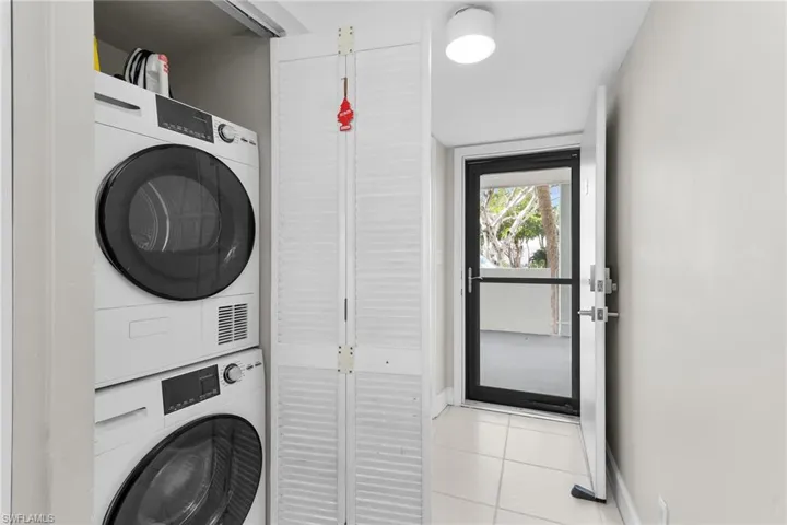 Laundry area with light tile patterned floors and stacked washing machine and dryer