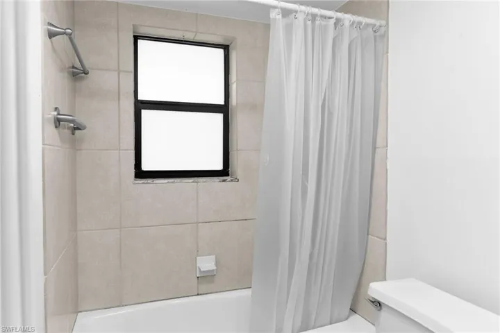 Bathroom with shower / bath combo with shower curtain and toilet