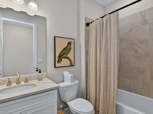 Light and bright guest bathroom with quartz vanity and tiled shower.