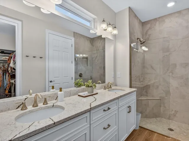 Primary bathroom with dual sinks, quartz countertops, and a spacious walk-in shower.