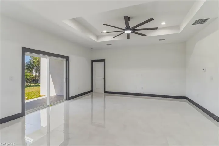Spare room with a tray ceiling, ceiling fan, light tile patterned floors, and recessed lighting