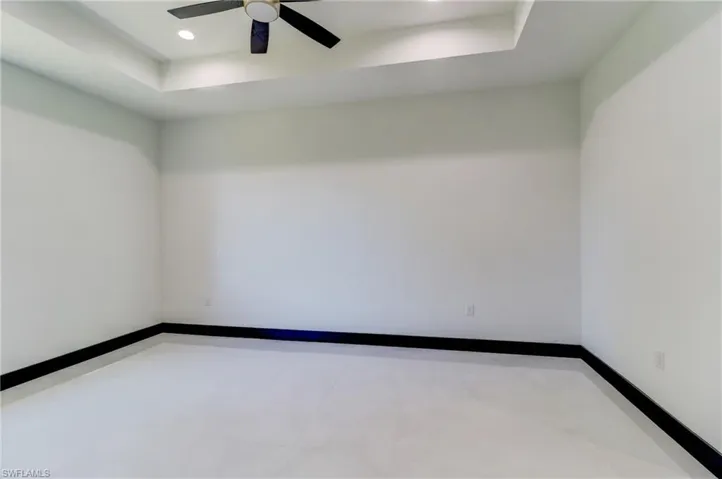 Empty room with a raised ceiling, ceiling fan, and recessed lighting