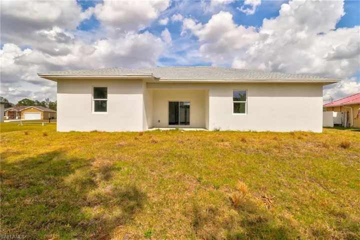 Back of property with stucco siding, a yard, a patio, and a shingled roof