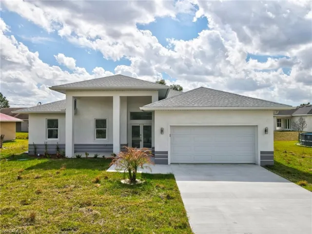 Prairie-style home with a front lawn, an attached garage, stucco siding, and driveway