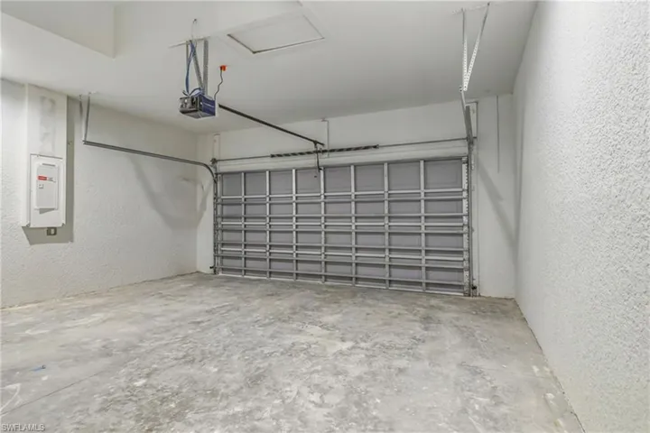 Garage featuring a textured wall, electric panel, and a garage door opener