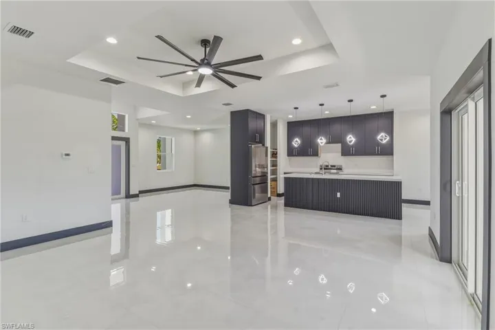 Kitchen featuring a ceiling fan, hanging light fixtures, a raised ceiling, modern cabinets, and light countertops