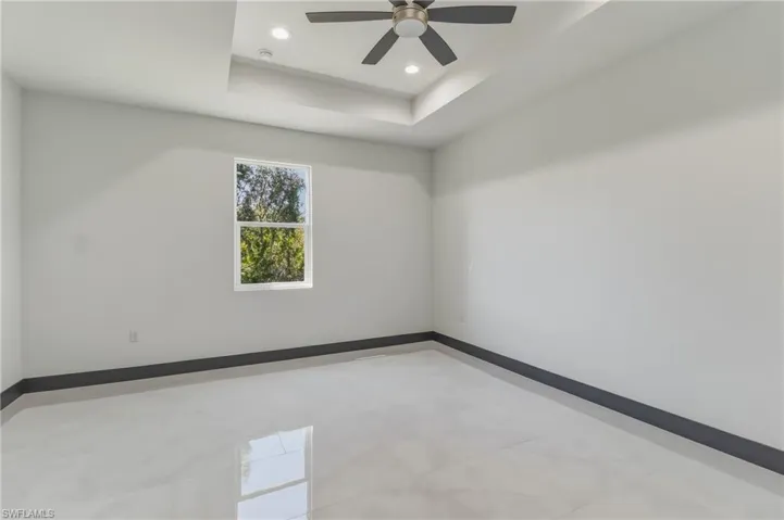 Empty room featuring a tray ceiling, recessed lighting, and a ceiling fan