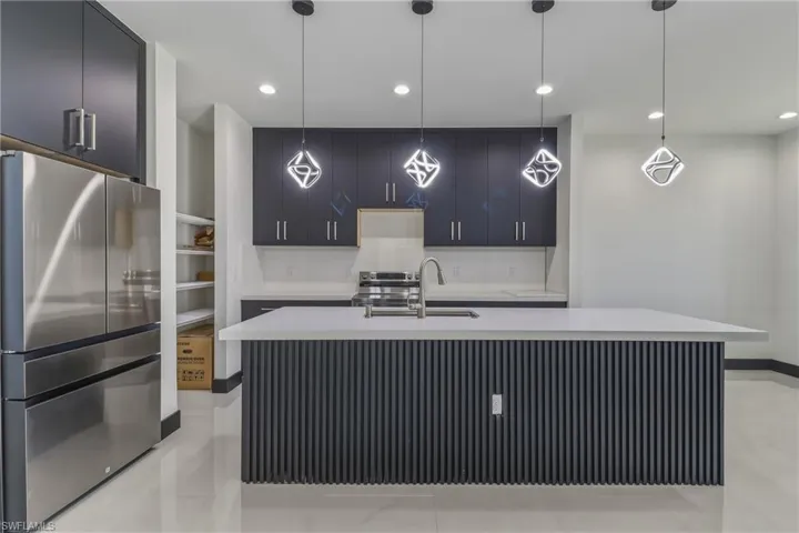 Kitchen with stainless steel appliances, modern cabinets, an island with sink, and hanging light fixtures