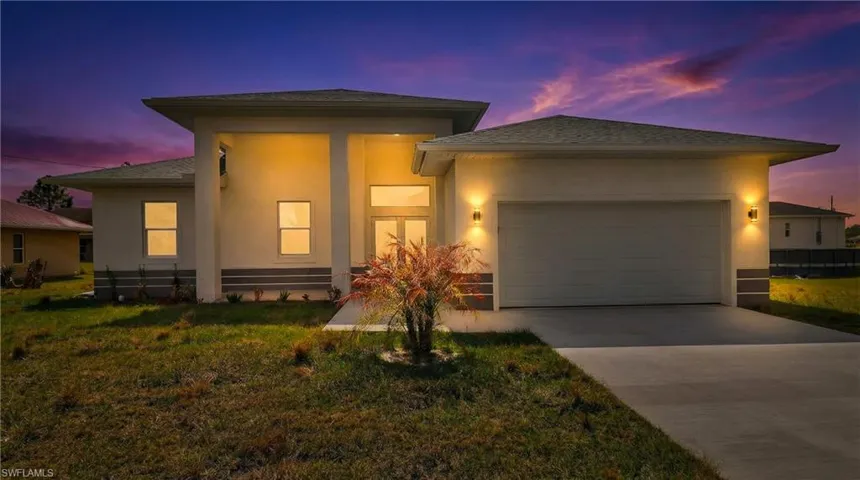 Prairie-style house with a garage, concrete driveway, a yard, and stucco siding