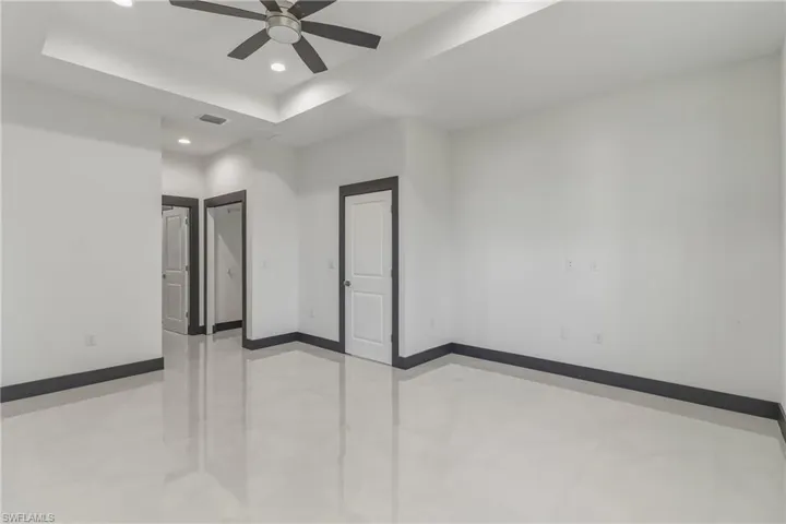 Spare room with a tray ceiling, ceiling fan, and recessed lighting