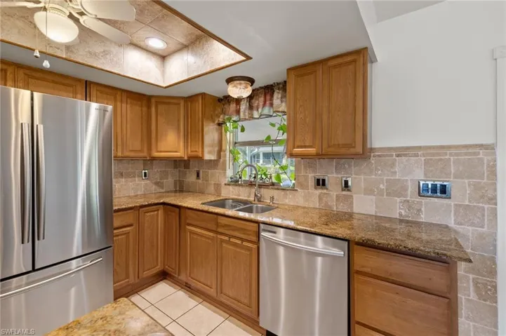 Kitchen featuring tasteful backsplash, ceiling fan, light tile floors, and stainless steel appliances