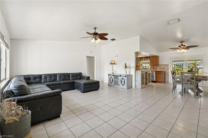 Living room with light tile flooring, ceiling fan, and vaulted ceiling