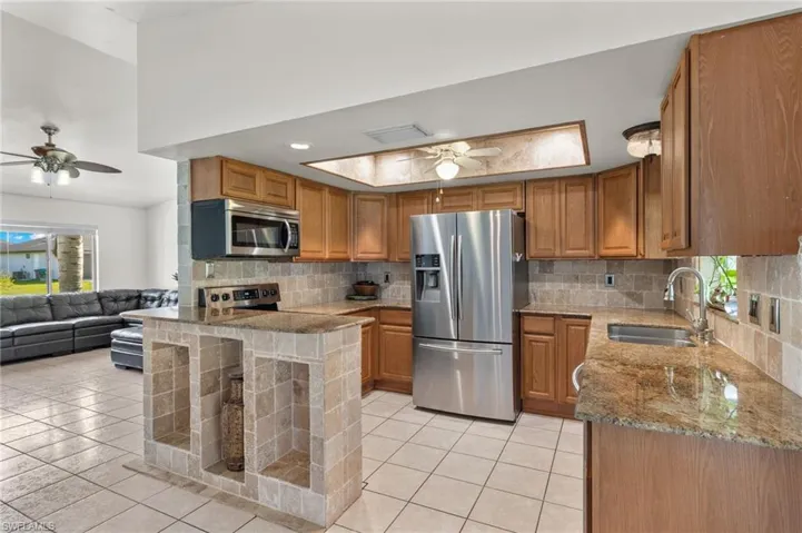 Kitchen featuring stainless steel appliances, sink, ceiling fan, and backsplash