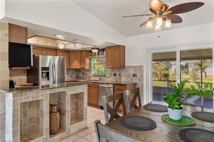 Kitchen featuring stainless steel appliances, vaulted ceiling, dark stone counters, and tasteful backsplash