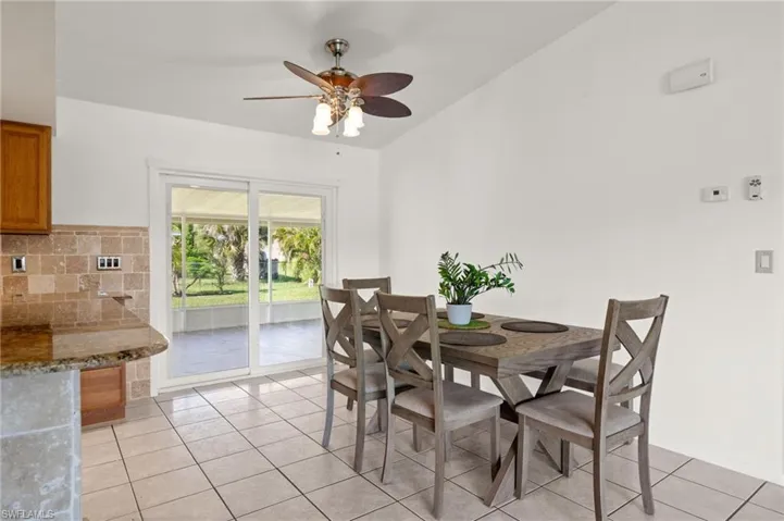 Tiled dining room with ceiling fan and lofted ceiling