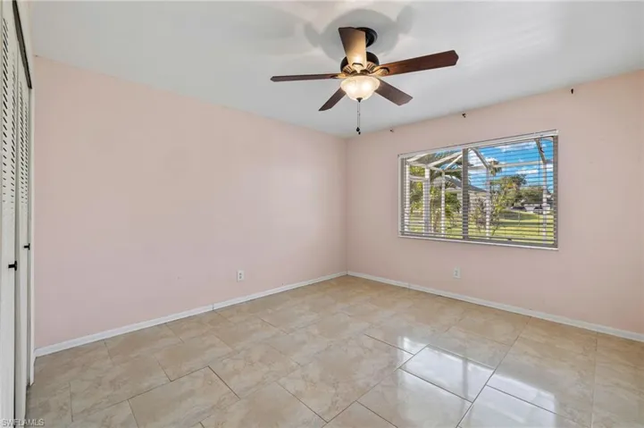 Empty room with ceiling fan and light tile flooring
