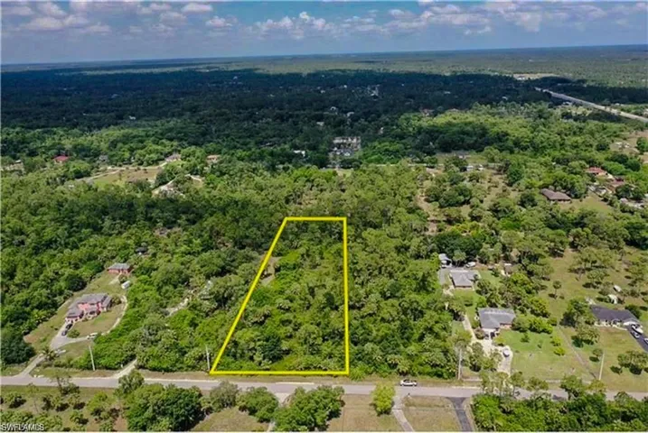 Aerial view of property and surrounding area featuring property boundaries highlighted and a heavily wooded area