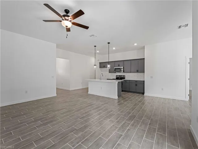 Unfurnished living room with hardwood / wood-style flooring, ceiling fan, and sink