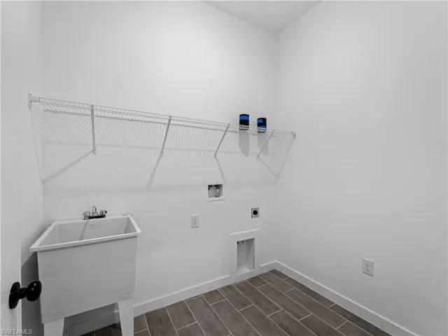 Laundry area featuring dark wood-type flooring, hookup for a washing machine, electric dryer hookup, and sink