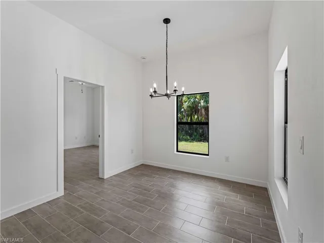 Unfurnished dining area featuring an inviting chandelier and dark hardwood / wood-style floors