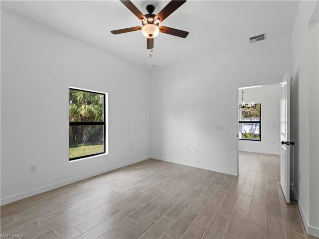 Unfurnished room with ceiling fan with notable chandelier and light hardwood / wood-style flooring