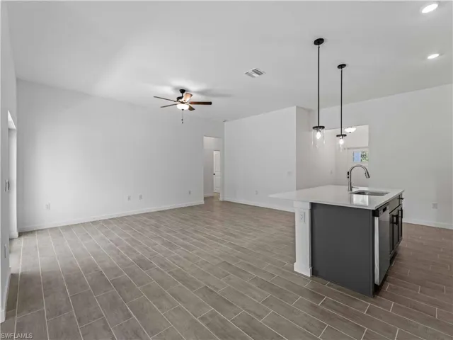 Kitchen featuring hanging light fixtures, sink, an island with sink, and dark hardwood / wood-style floors