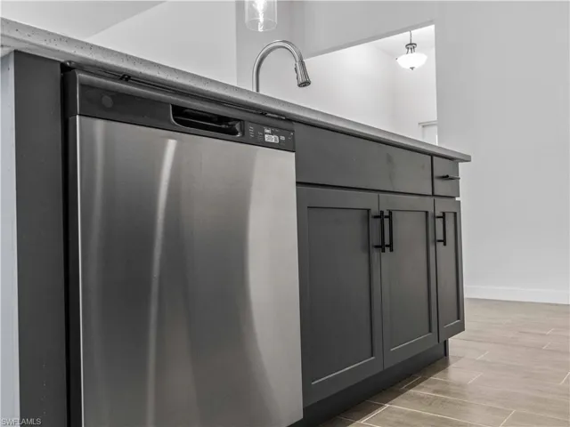 Kitchen featuring dishwasher, hardwood / wood-style floors, decorative light fixtures, and gray cabinetry