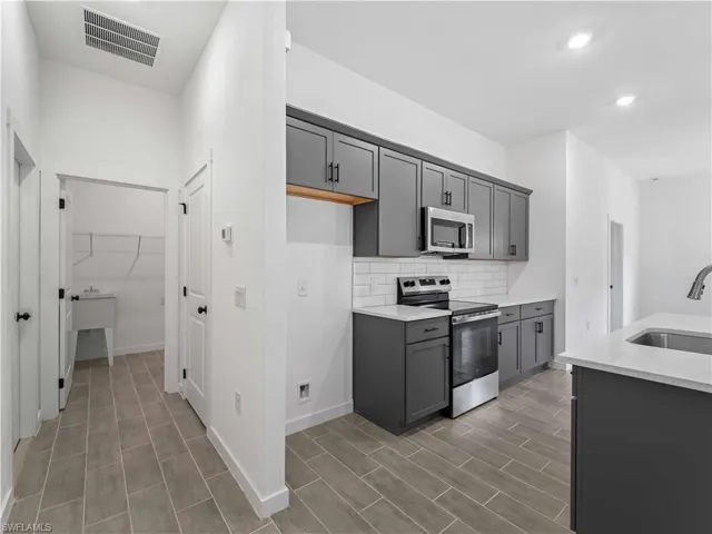 Kitchen with stainless steel appliances, sink, dark hardwood / wood-style floors, and gray cabinetry