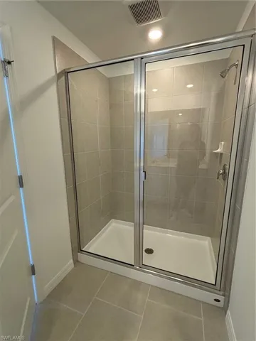 Bathroom featuring light tile patterned flooring, a shower stall, and recessed lighting