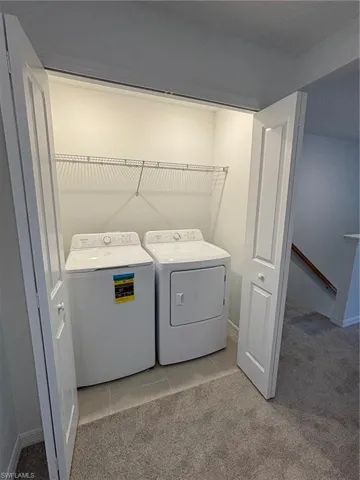 Washroom featuring light carpet, washer and clothes dryer, and light tile patterned flooring