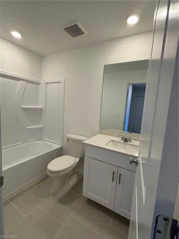 Bathroom with vanity, recessed lighting, shower / bath combination, and light tile patterned flooring