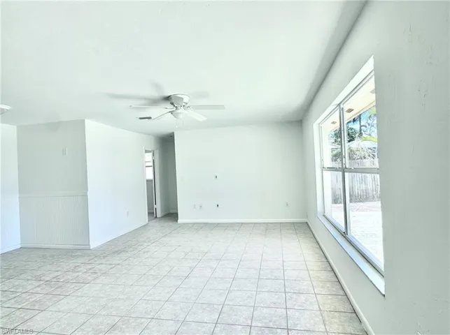 Empty room featuring ceiling fan, light tile patterned floors, and baseboards