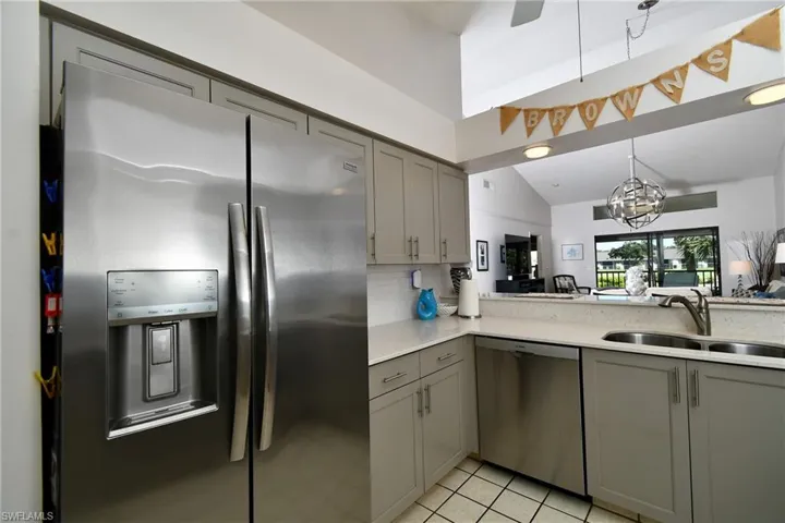 Kitchen with gray cabinetry, stainless steel appliances, light stone counters, a chandelier, and tasteful backsplash