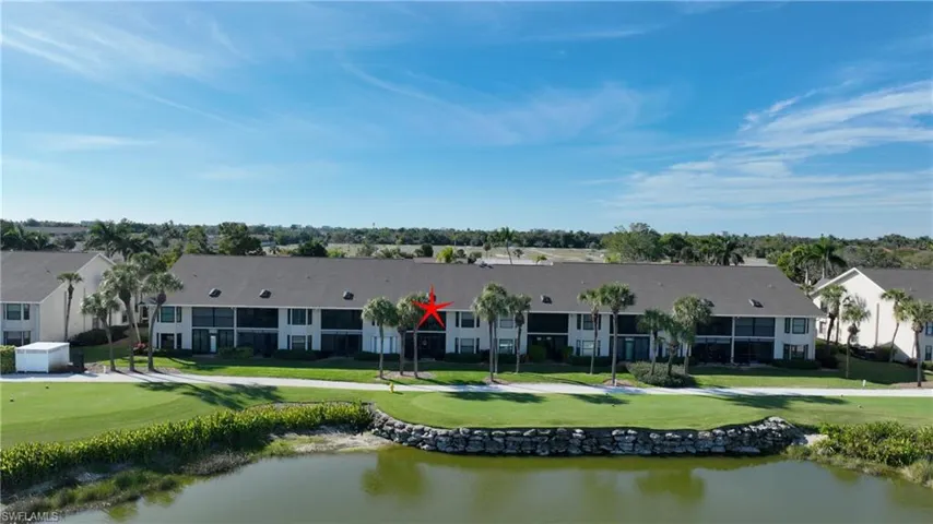 Back of property with a water view, a yard, and view of golf course