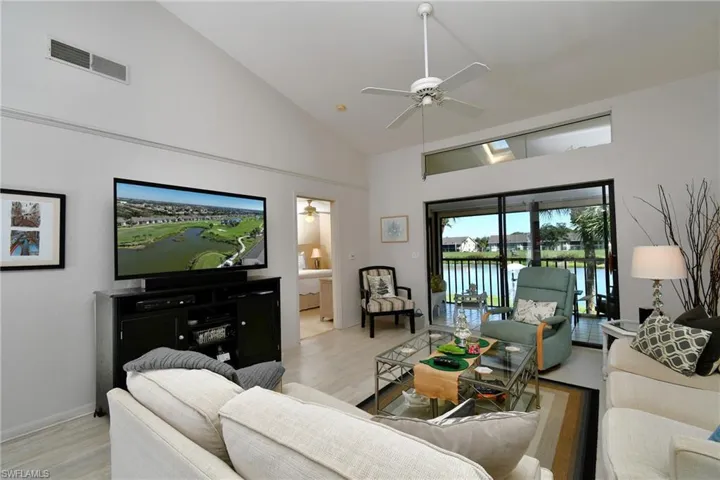 Living area featuring high vaulted ceiling, ceiling fan, and light wood-style floors