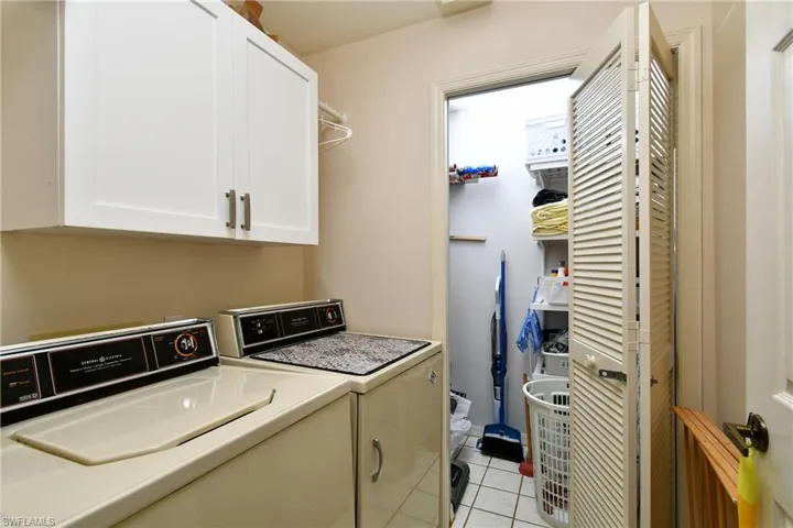 Laundry area featuring cabinet space, light tile patterned floors, and independent washer and dryer