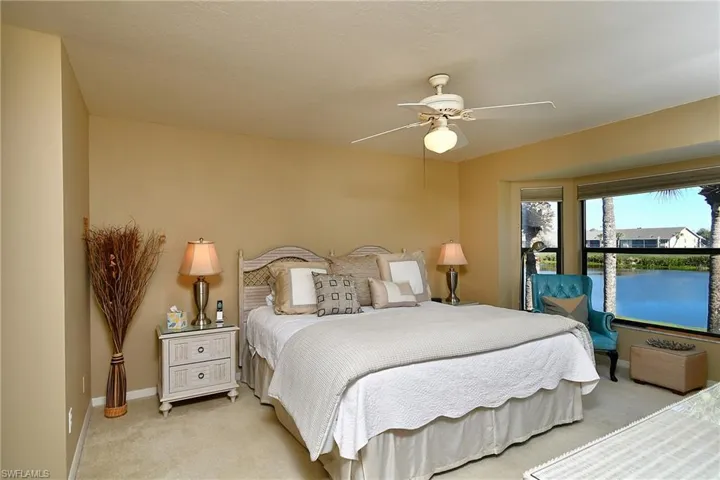 Carpeted bedroom featuring a ceiling fan and a water view