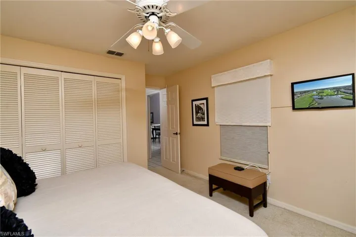 Bedroom featuring light colored carpet, ceiling fan, and a closet