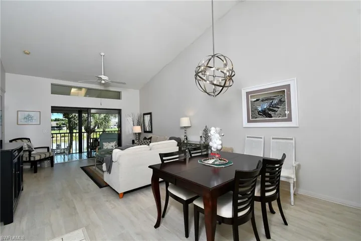 Dining space featuring high vaulted ceiling, light wood finished floors, a chandelier, and ceiling fan