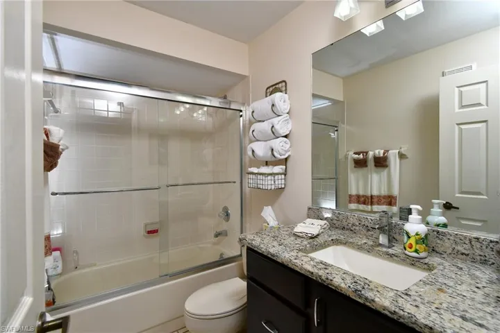 Bathroom featuring vanity and bath / shower combo with glass door