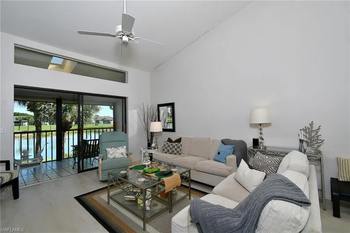 Living area with a water view, wood finished floors, high vaulted ceiling, and a ceiling fan