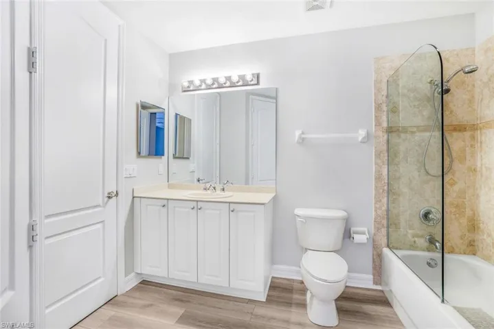 Bathroom with shower / bath combination, vanity, and light wood finished floors