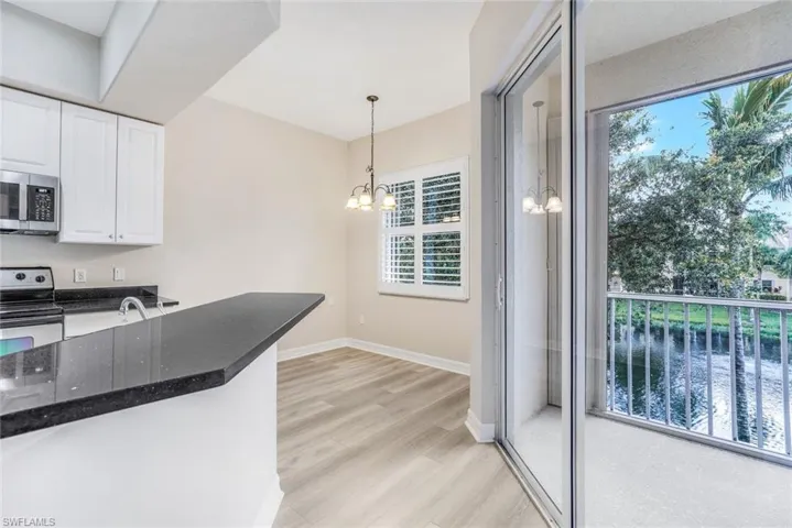 Kitchen featuring pendant lighting, appliances with stainless steel finishes, white cabinets, dark stone countertops, and a chandelier