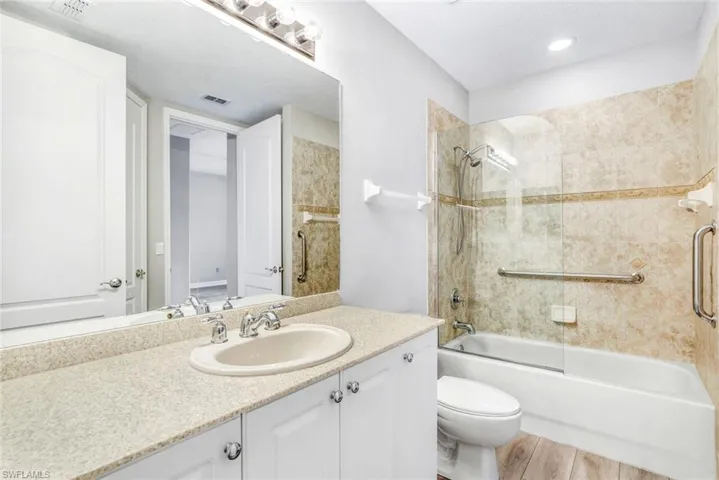 Full bath with washtub / shower combination, vanity, light wood-style flooring, and a textured ceiling