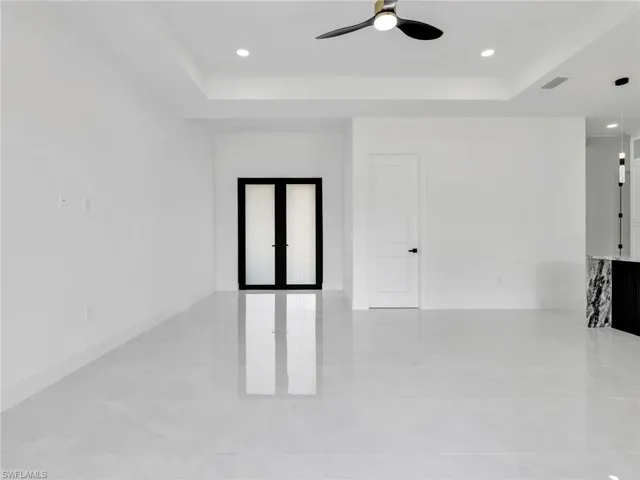 Unfurnished room with french doors, ceiling fan, recessed lighting, and a tray ceiling