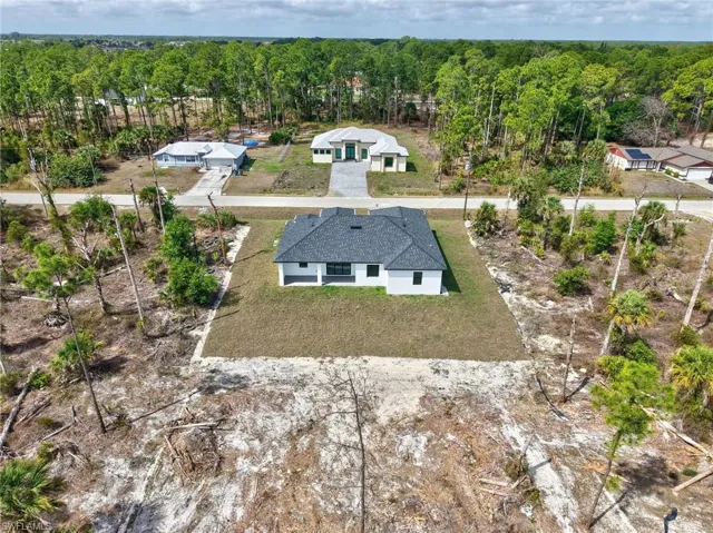Aerial view of property and surrounding area with a forest