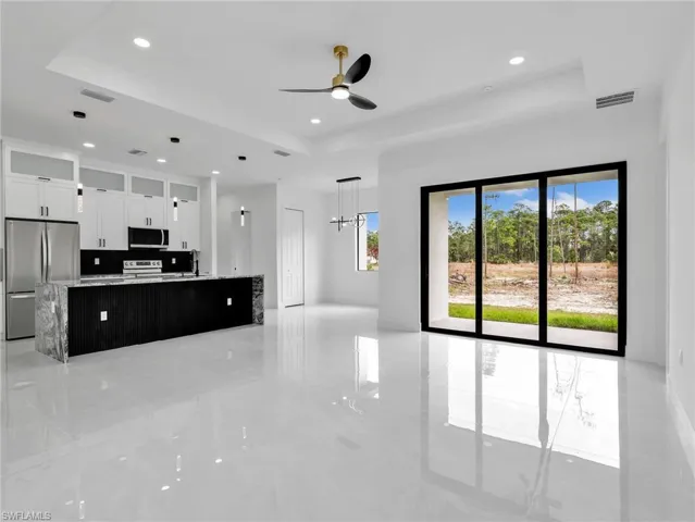 Unfurnished living room featuring a ceiling fan, a tray ceiling, and recessed lighting